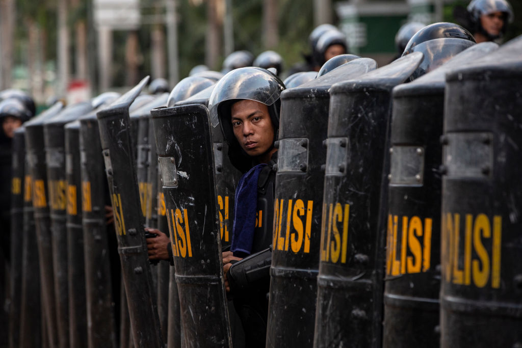 Police take cover during a 2019 rally in front of the People's Representative Council against the proposed criminal code ( Oscar Siagian/Getty Images)