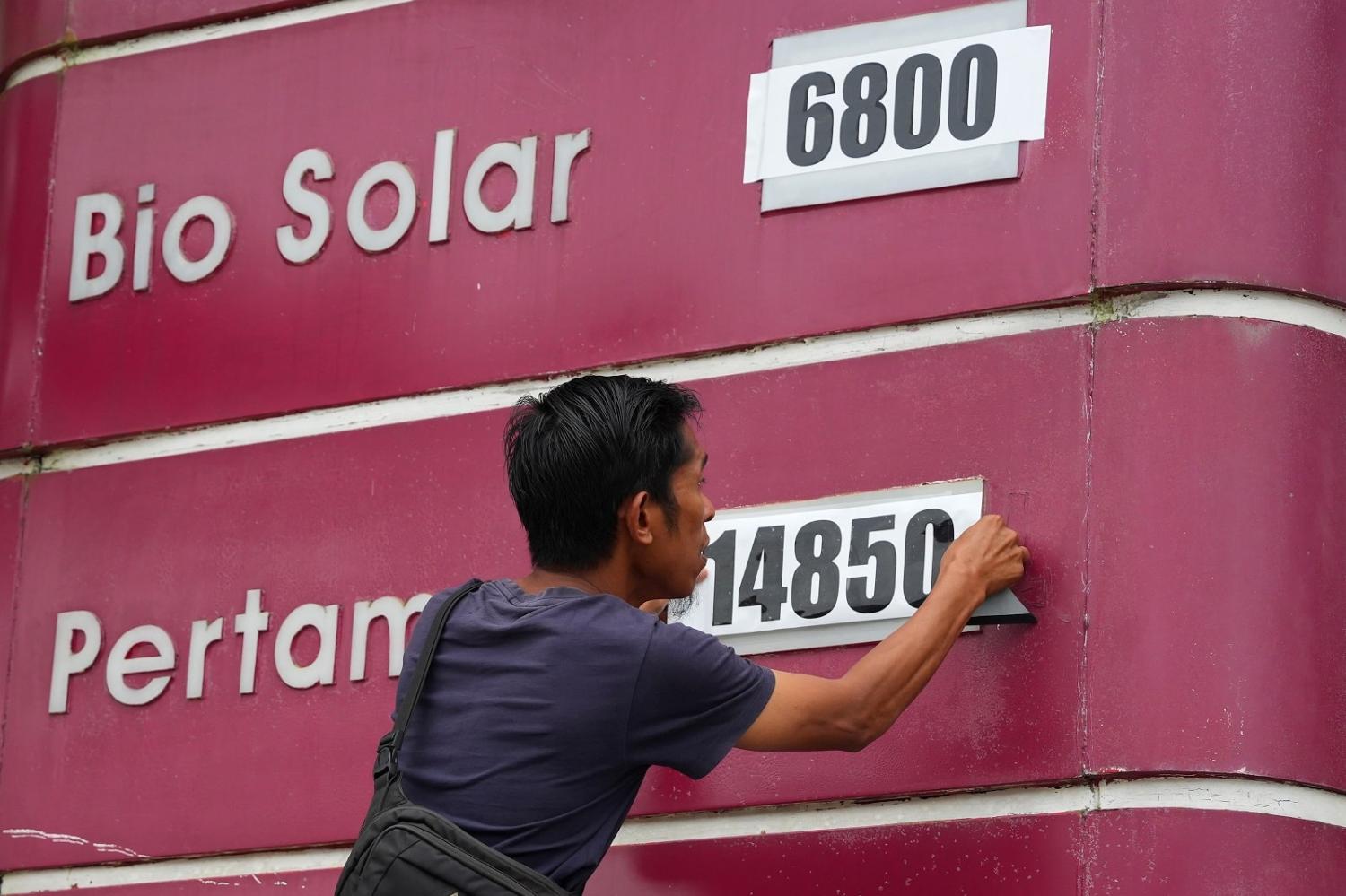 A worker changes the fuel price at a petrol station in Pangkal Pinang, Indonesia, 4 September 2022 (Dimas Ardian/Bloomberg via Getty Images)