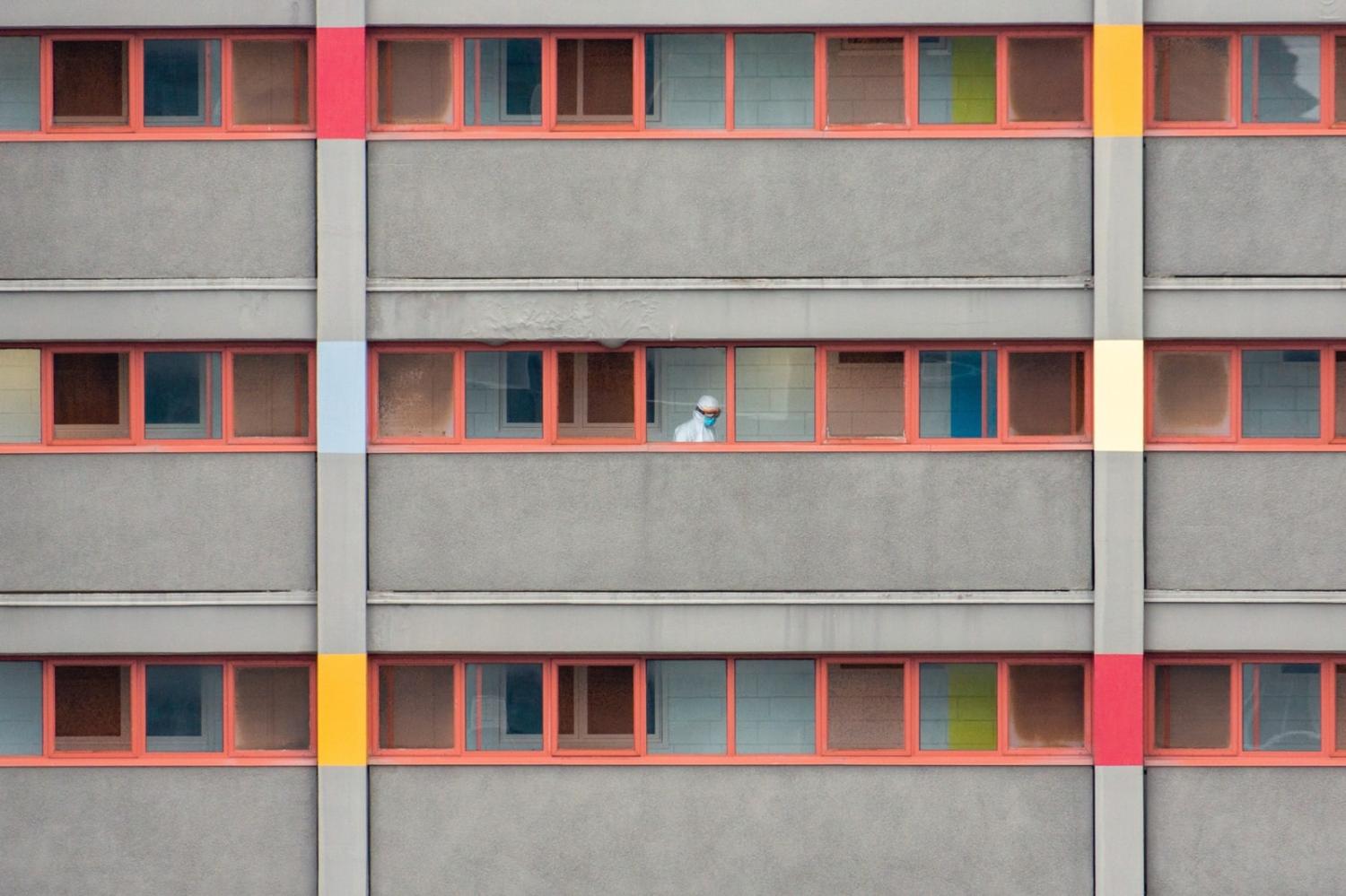 A worker in full personal protection equipment at a locked-down residential housing tower in North Melbourne (Chris McLay/Unsplash)