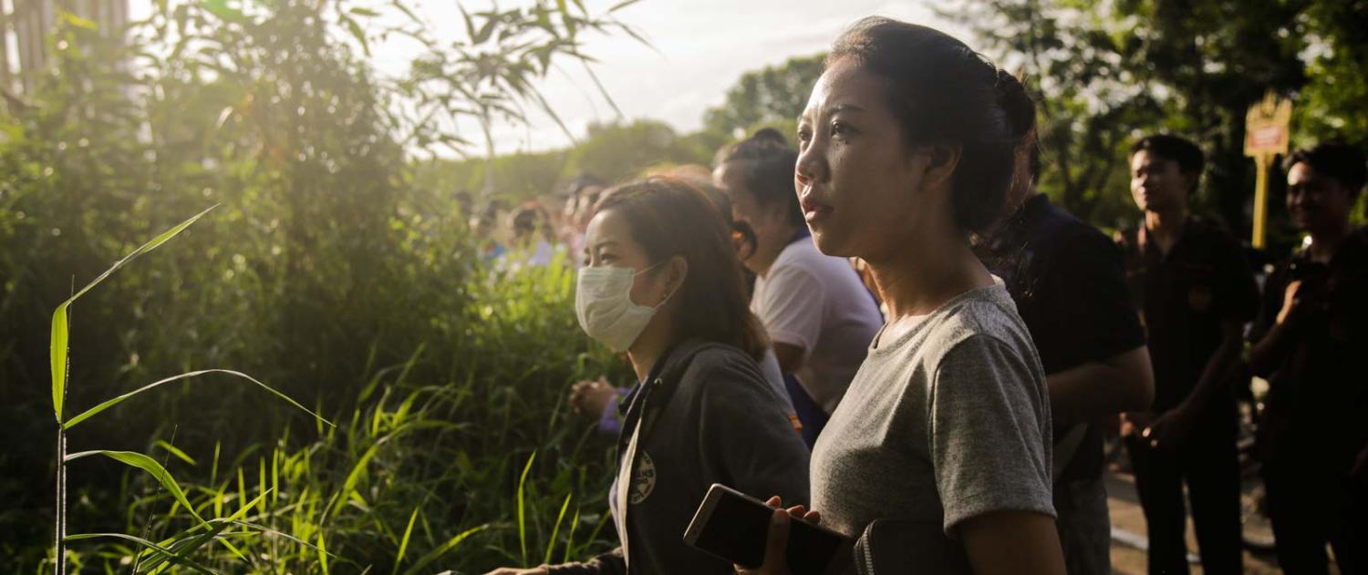 Onlookers watch as a helicopter flies towards Tham Luang Nang Non cave, Chian Rai, Thailand (Photo: Lauren DeCicca/Getty Images)