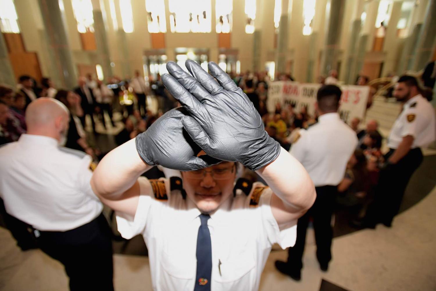 A security guard blocks photographers during a protest as parliament passes data-encryption legislation, Canberra, December 2018 (Photo: Tracey Nearmy/Getty Images)