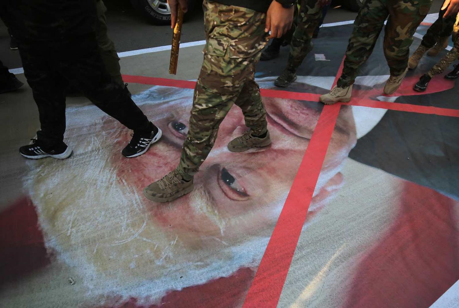 Iraqi Popular Mobilisation Forces members walk on a portrait of US President Donald Trump in Baghdad following the killings of Iranian commander Qassem Soleimani and Iraqi commander Abu Mahdi Al-Muhandis, 6 January (Photo: Ahmad al-Rubaye/AFP via Getty)