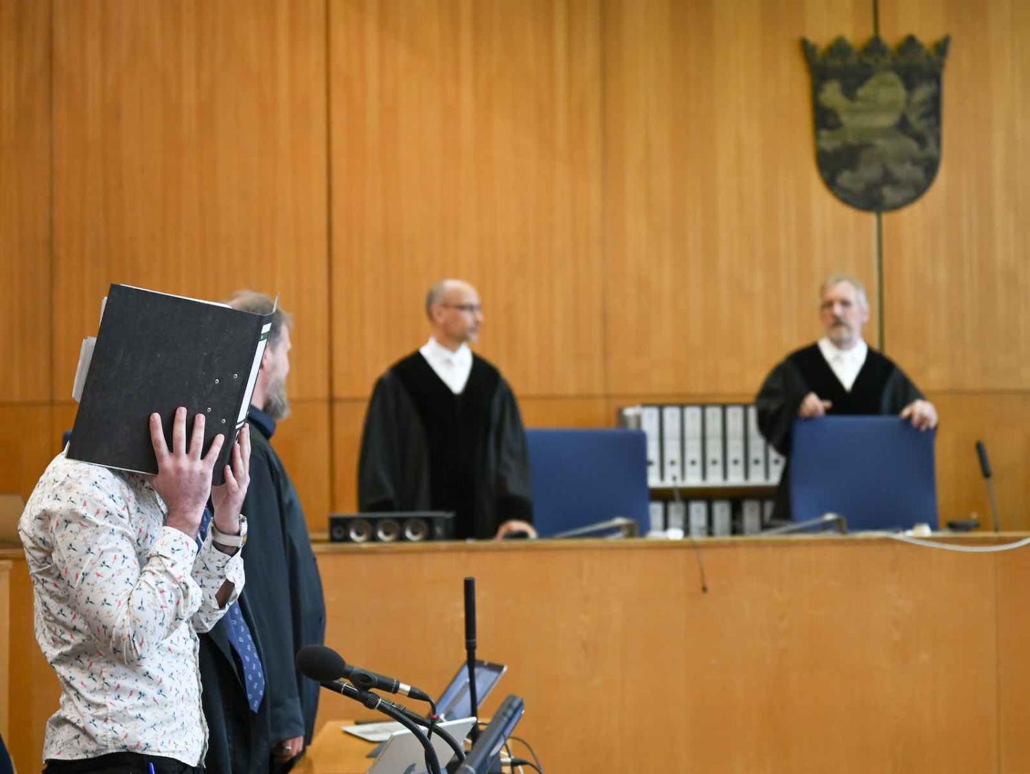 A defendant, identified only as Taha al-J, hides his face for the start of his trial on 24 April on charges of genocide and murdering a Yazidi girl held as a slave (Arne Dedert/AFP via Getty Images)