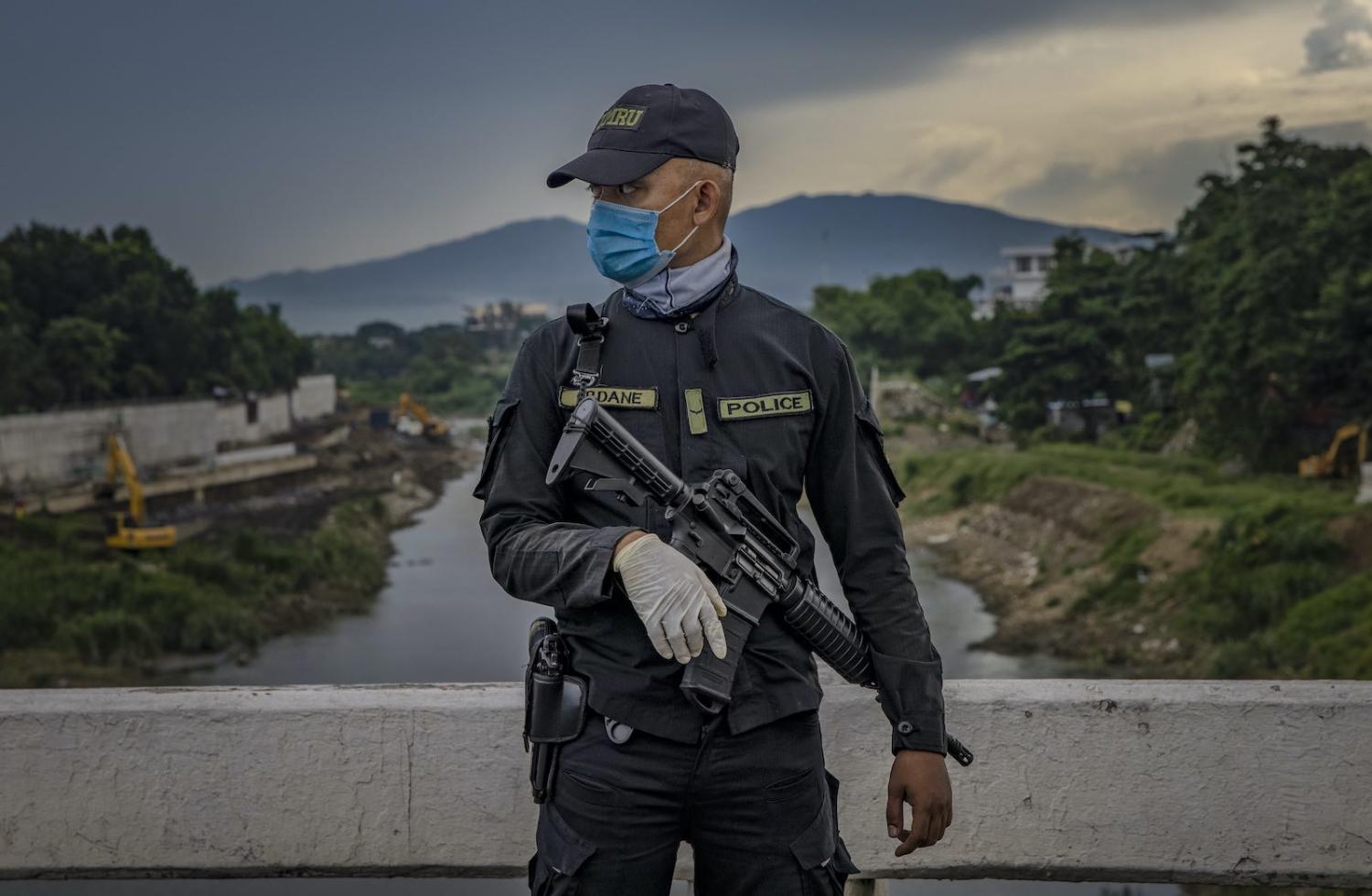 A police officer stands guard at a quarantine checkpoint in Quezon city, Philippines, 4 August 2020 (Ezra Acayan/Getty Images)