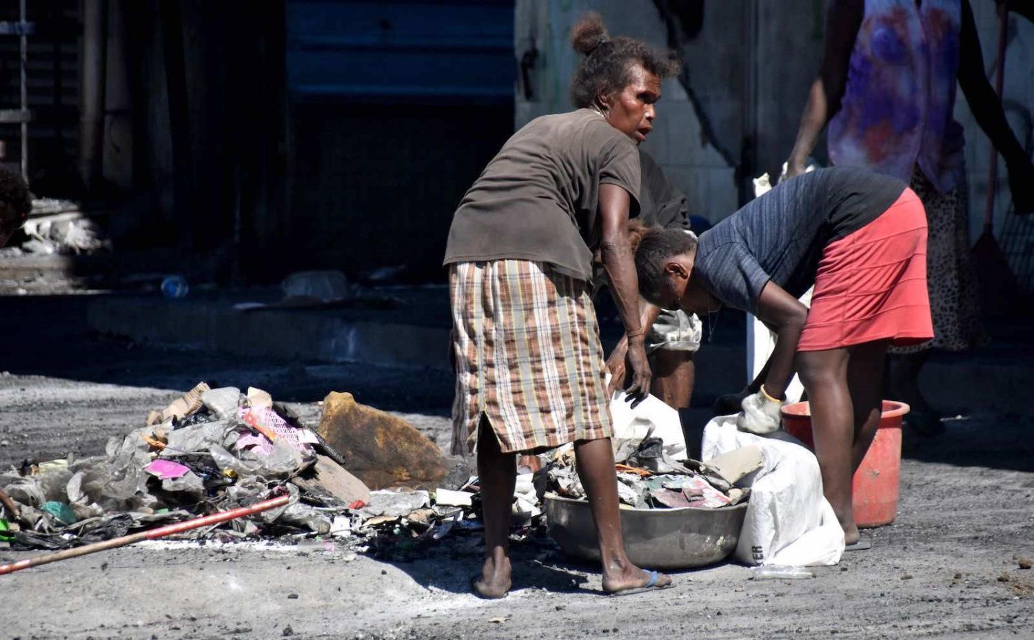 Clearing debris from the streets in Honiara’s Chinatown on 28 November 2021 (Charley Piringi/AFP via Getty Images)