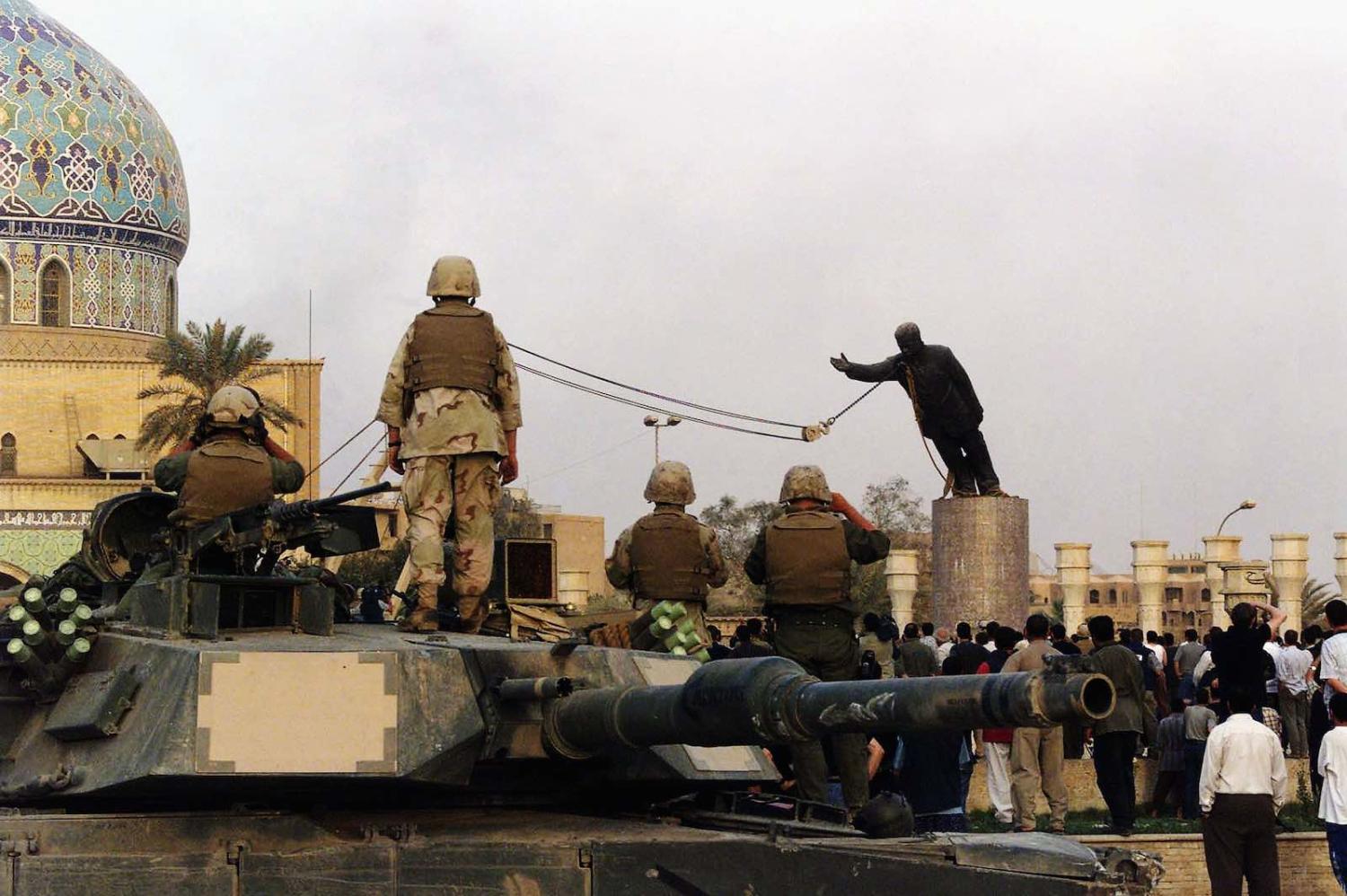 US marines and Iraqis watch the toppling of Saddam Hussein’s statue in al-Fardous square in Baghdad, 9 April 2003 (Wathiq Khuzaie /Getty Images)