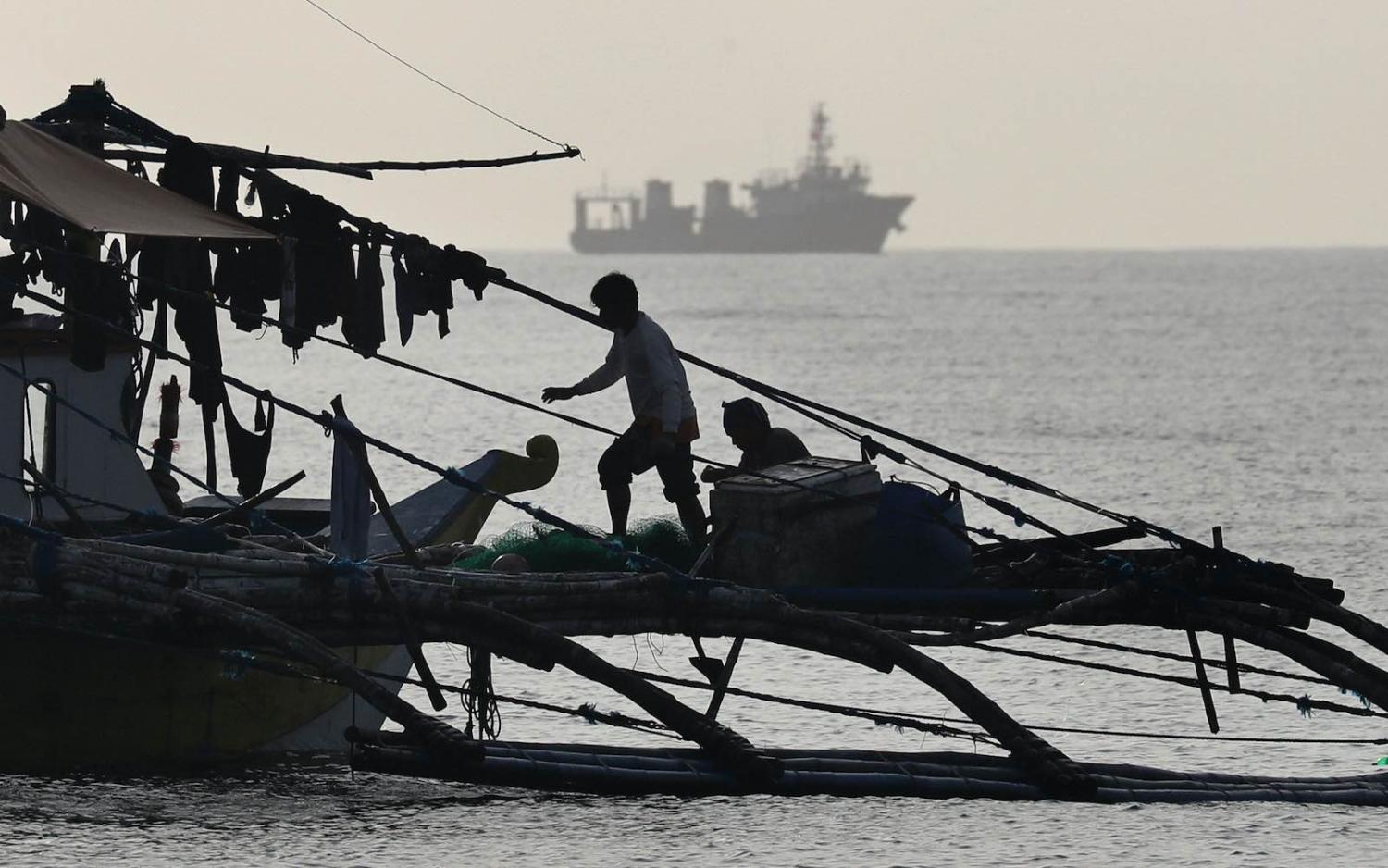 Filipino fishermen on the Scarborough Shoal as a Chinese Coast Guard ship passes nearby, December 2016 (The Asahi Shimbun via Getty Images)