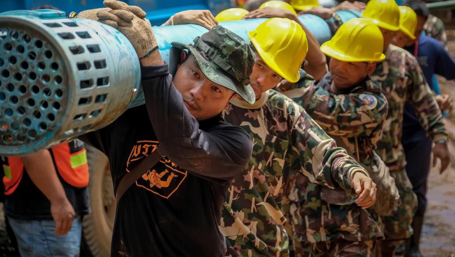 Rescue workers carry heavy water pumping gear into Tham Luang Nang Non cave, northern Thailand (Photo: Linh Pham/Getty)