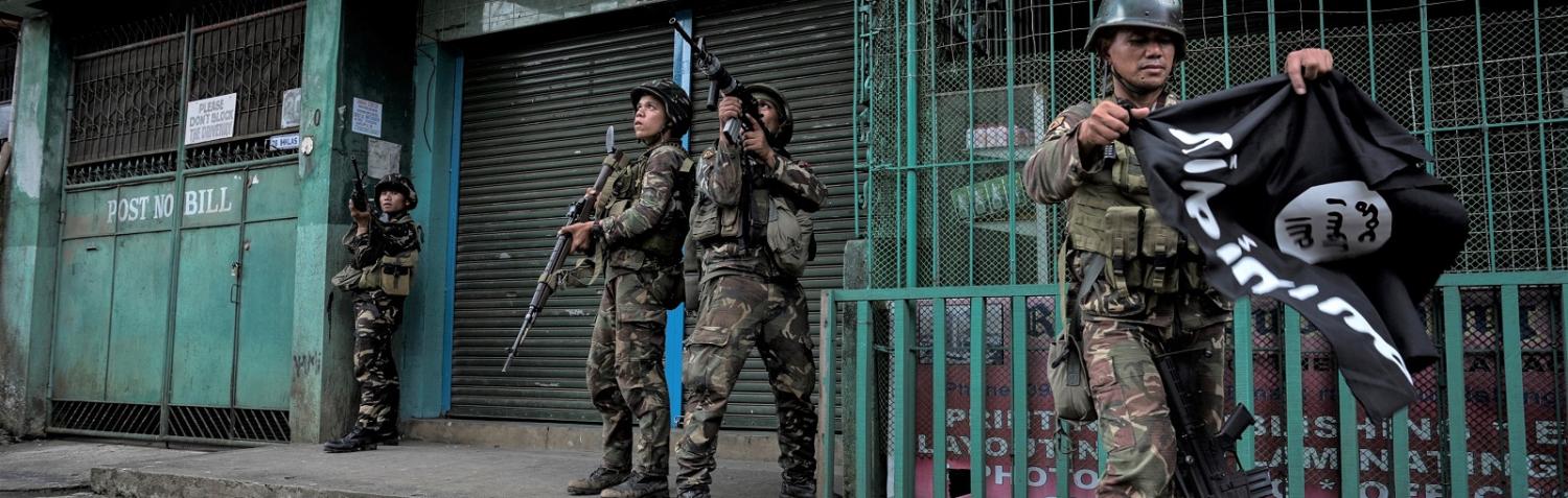 A soldier carrying a captured ISIS flag while clearing a city street of militants on 26 May in Marawi city, southern Philippines (Photo: Jes Aznar/Getty)