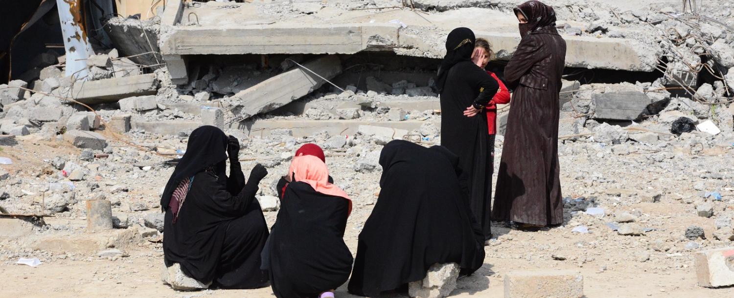 Women wait in front of building debris as Iraqi civilians head for shelter in Mosul on 26 March. (Photo by Hamit Huseyin/Getty Images)