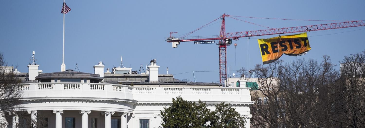 An anti-Trump sign saying ‘resist’ hung from a crane by Greenpeace seen behind the White House. (Photo by Samuel Corum/Anadolu Agency/Getty Images)